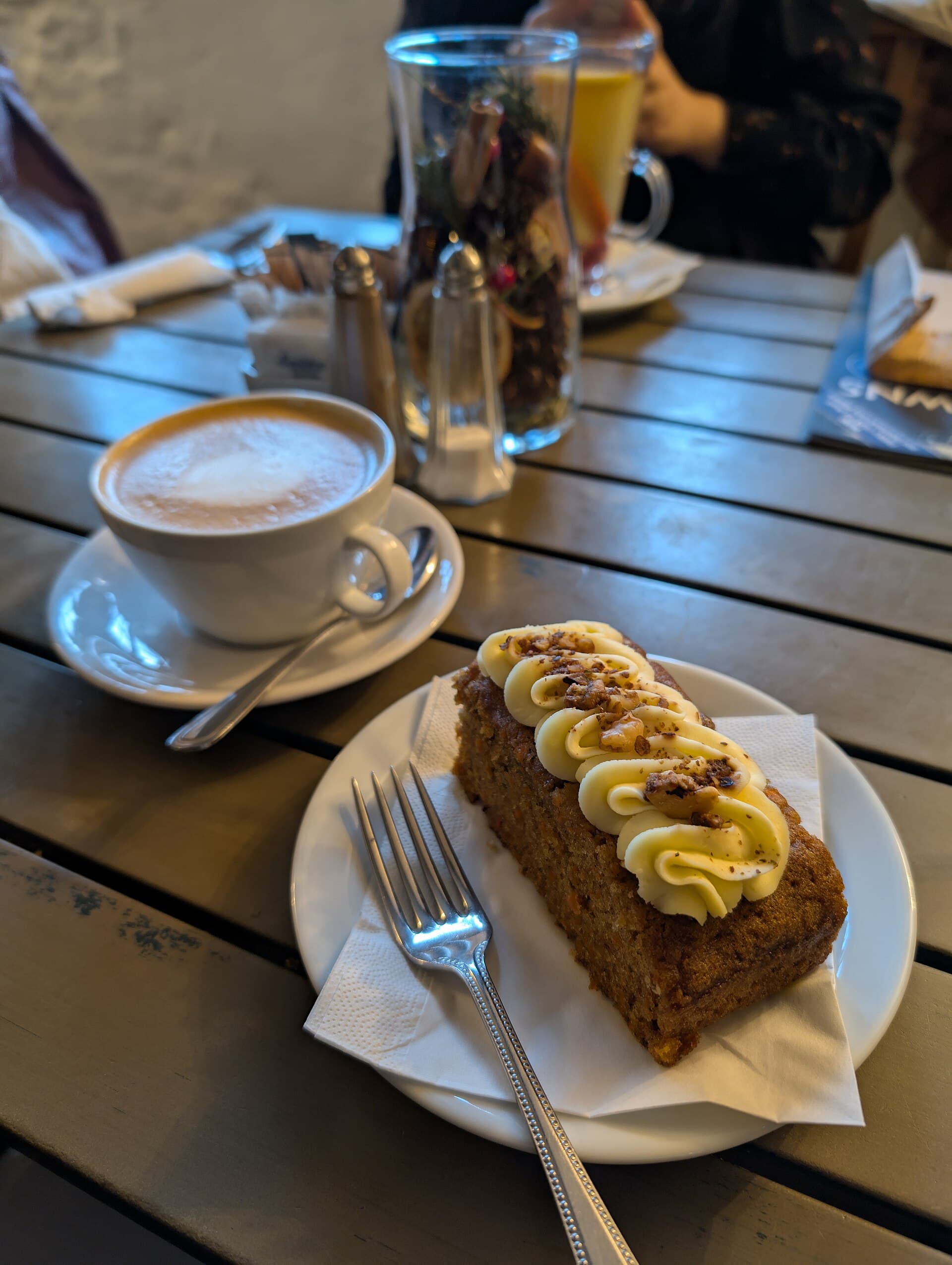 A slice of carrot cake beside a latte.