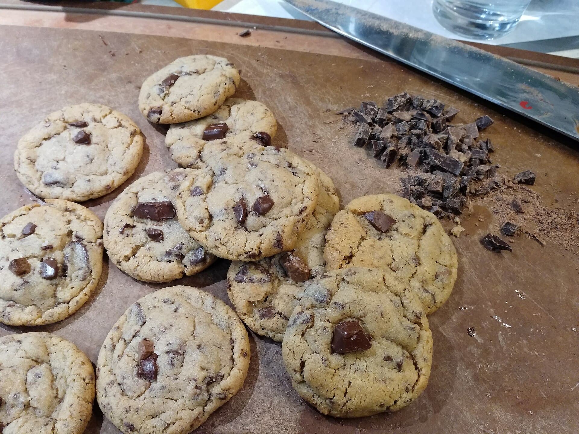 Freshly baked chocolate chip cookies cooling on a board.